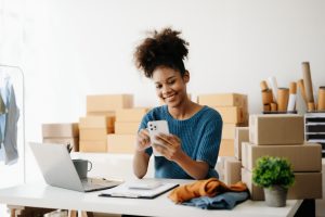Young African business owner woman prepare parcel box and standing check online orders for deliver to customer on tablet, laptop Shopping Online concept.